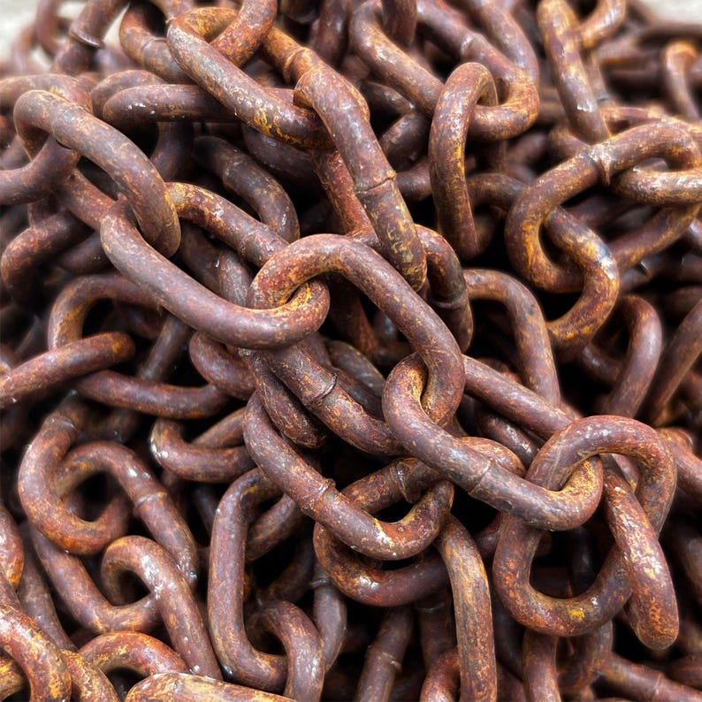 May include: Close-up of a pile of rusty metal chains. The chains are a deep reddish-brown color, with visible rust and wear. The links are thick and heavy, suggesting industrial use or decorative purposes.