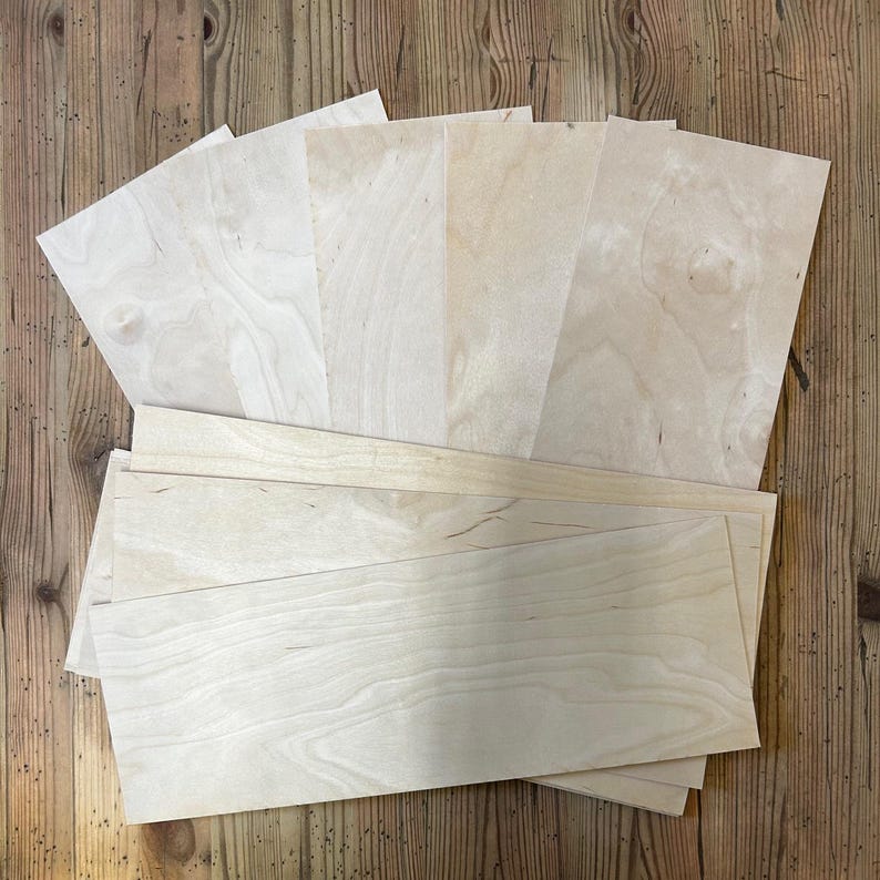 Op de afbeelding: Een stapel dunne, lichte houtfineerplaten in verschillende maten. Het hout heeft een natuurlijke nerf en is licht beige van kleur.