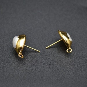 Könnte beinhalten: Ein Paar goldfarbene Ohrringe mit weißen perlmuttartigen Steinen. Die Ohrringe haben ein schlichtes Design und sind perfekt für den Alltag.