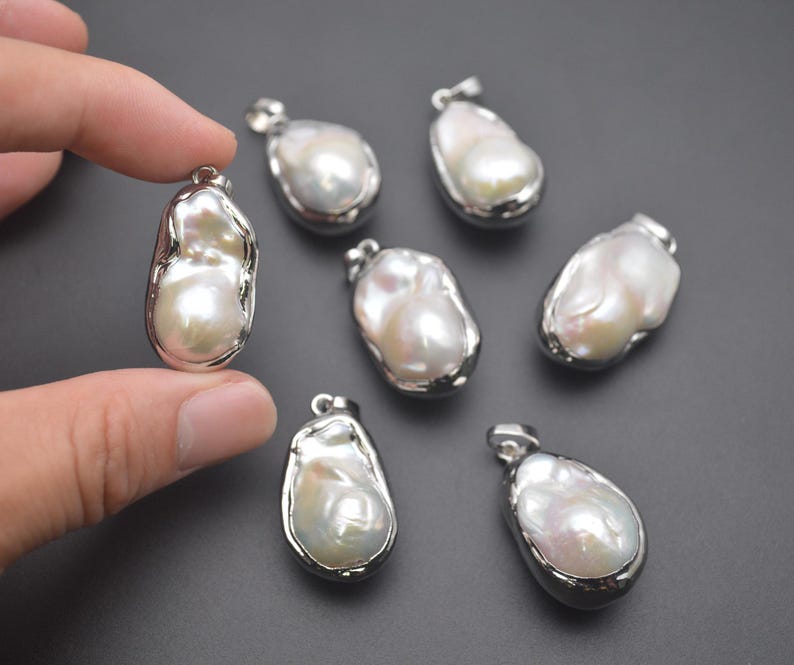 May include: Seven white baroque pearl pendants with silver settings. The pearls are irregular in shape and have a smooth, glossy finish.