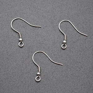May include: Three silver earring hooks with a small ball at the end of each hook.