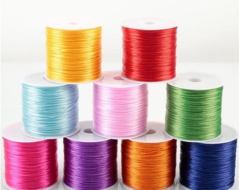 May include: Assortment of eight spools of colorful elastic string, each wound around a white plastic spool. The colors are yellow, red, light blue, pink, green, purple, orange, and navy blue.