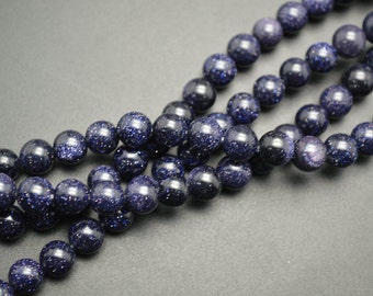 May include: A strand of blue gemstone beads with a sparkly, speckled finish. The beads are round and have a smooth, polished surface.