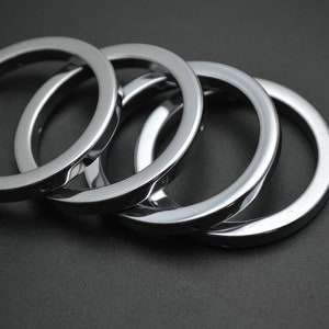 May include: Four silver metal rings of different sizes stacked on top of each other.