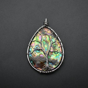 May include: A silver wire wrapped pendant featuring a tree of life design with a iridescent abalone shell inlay.
