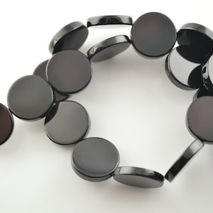 May include: A strand of black onyx beads, each bead is a flat, round disc.