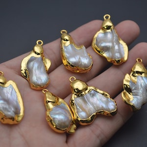 May include: Seven gold-tone pendants featuring irregular shaped white baroque pearls. Each pendant has a loop for attaching to a chain or cord.