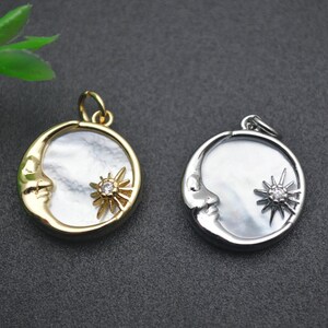 Op de afbeelding: Twee maan- en zon hangers, een gouden en een zilveren, met een witte parelmoer inleg en een heldere strass ster.