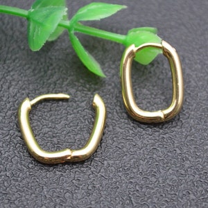 May include: A pair of gold-toned hoop earrings with a slightly rectangular shape.