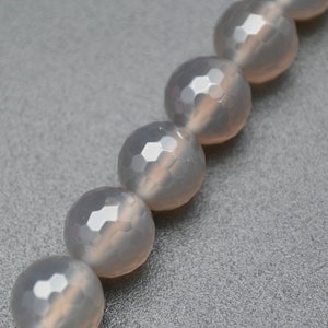 May include: A strand of light grey faceted gemstone beads. The beads are round and have a smooth, polished finish.