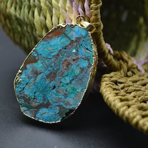 May include: A gold pendant with a blue and brown agate stone. The stone has a unique pattern of swirls and veins.