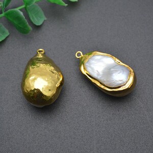 May include: Two gold-tone pendant charms with a baroque pearl design. One charm is solid gold, and the other has a white pearl insert.