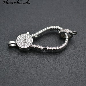 Op de afbeelding: Zilverkleurige sluiting met een rond, pavé-gezet kristalontwerp. De sluiting is ontworpen voor gebruik met kettingen of armbanden.