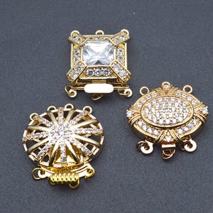Peut inclure: Trois fermoirs en métal doré avec des embellissements en cristal transparent. Les fermoirs sont conçus pour être utilisés comme fermoirs de bijoux.