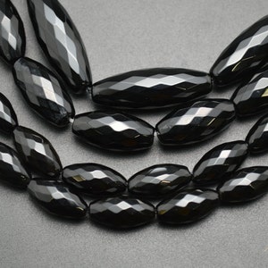 May include: A strand of black faceted gemstone beads. The beads are oval shaped and have a glossy finish.