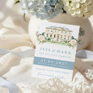 Puede incluir: Una tarjeta de invitación de boda con una ilustración en acuarela de una mansión, con el texto "JESS & MARK ARE GETTING MARRIED 21.05.2027." La tarjeta está decorada con detalles florales y sobre un fondo de flores y cintas.