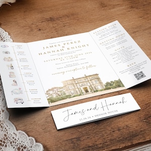 May include: A tri-fold wedding invitation with gold text and a watercolor illustration of a stately home. A smaller card with the names "James and Hannah" is below the invitation. The invitation is on a wooden surface.