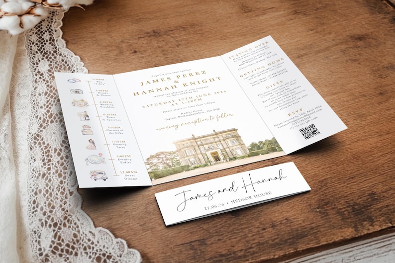 May include: A tri-fold wedding invitation with gold text and a watercolor illustration of a stately home. A smaller card with the names "James and Hannah" is below the invitation. The invitation is on a wooden surface.