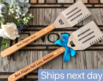 May include: Two wooden handled spatulas with stainless steel blades. The handles are engraved with the text "Best Flippin Dad!" and "Best Flippin Dad! Love, Madeline".