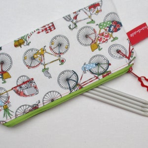 Könnte beinhalten: Ein weißes Federmäppchen mit grünem Reißverschluss und Fahrradmuster. Das Etui enthält mehrere Stricknadeln und ein rotes Etikett mit der Aufschrift "handmade".