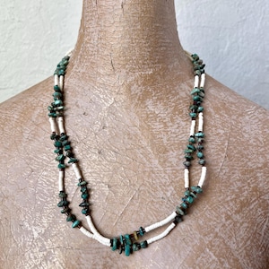 May include: A double-strand necklace made of turquoise and white beads. The turquoise beads are a light green color and the white beads are a creamy white.