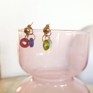 May include: Gold earrings with a small round bead and a larger round bead in pink, blue, green, and light green.