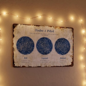 Może przedstawiać: Prostokątna tablica ścienna z trzema okrągłymi niebieskimi mapami gwiazd z napisem Charlene & Patrick, YOU ARE MY SUN, MY MOON, AND ALL MY STARS, Met, Engaged i Married wraz z datami i lokalizacjami, otoczona ciepłymi lampkami sznurkowymi.