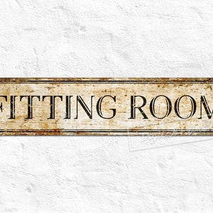 May include: A vintage-style metal sign with a distressed, brown background and black lettering that reads "FITTING ROOM".