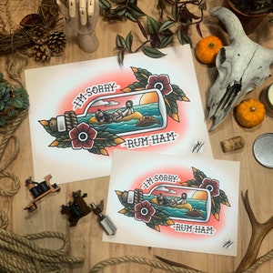 Op de afbeelding: Twee tattoo-flashontwerpen van een boodschap in een fles. De fles is blauw met een kurkstop en bevat drie figuren. De boodschap luidt "I'm sorry - Rum Ham". De ontwerpen zijn in een traditionele tattoo-stijl met rode bloemen en groene bladeren.