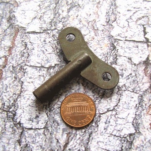 Op de afbeelding: Een vintage metalen sleutel om een ​​klok op te winden. De sleutel is ongeveer zo groot als een Nederlandse cent.