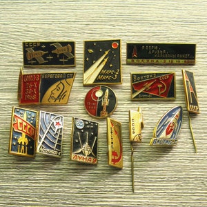 May include: A collection of 14 vintage Soviet space program enamel pins. The pins feature various spacecraft, rockets, and astronauts, including the Soyuz, Vostok, and Mars spacecraft. The pins are in excellent condition and would be a great addition to any space enthusiast's collection.