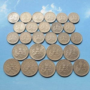 Puede incluir: Una colección de 20 monedas británicas de cinco peniques de plata. Las monedas presentan un diseño de una corona y un cardo. Las monedas están dispuestas en círculo con las monedas más nuevas en el centro.