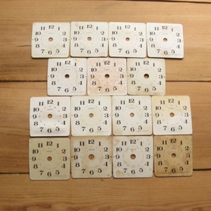 Peut inclure: Une collection de 16 cadrans d'horloge blancs avec des chiffres et des aiguilles noirs. Les cadrans d'horloge sont disposés en quatre rangées de quatre. Chaque cadran d'horloge a un diamètre d'environ 5 cm.