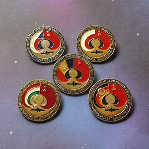 May include: Five round, gold-colored pins with red, white, blue, and green enamel. Each pin features a stylized image of a spacecraft with a red star and the text "ПЕРВЫЙ СОВЕТСКО" in Cyrillic script.