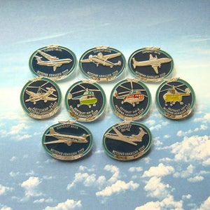 Puede incluir: Diez pines redondas, azules y plateadas con imágenes de varios aviones y helicópteros. Cada pin tiene un borde blanco y un texto en ruso que dice "Historia de la aviación de la URSS".