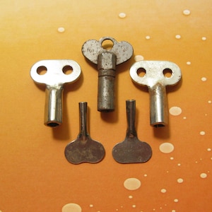 May include: Five vintage metal keys for winding up toys. The keys are silver and have different shaped heads.