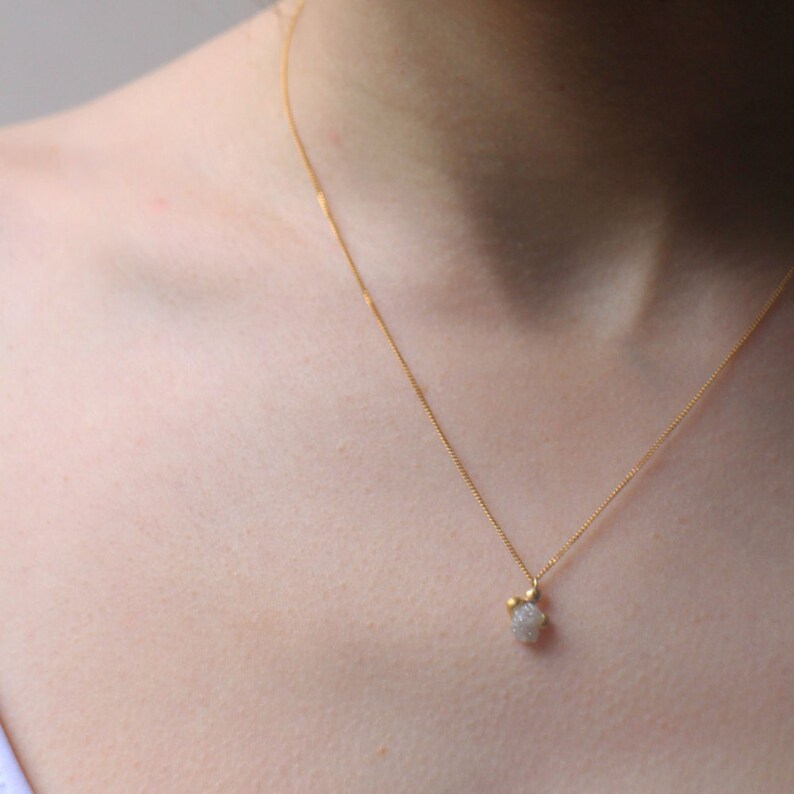 May include: A delicate gold chain necklace with a small, white, sparkly pendant.