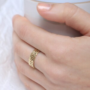 May include: A gold ring with a unique design featuring a double row of small, round, connected pieces.