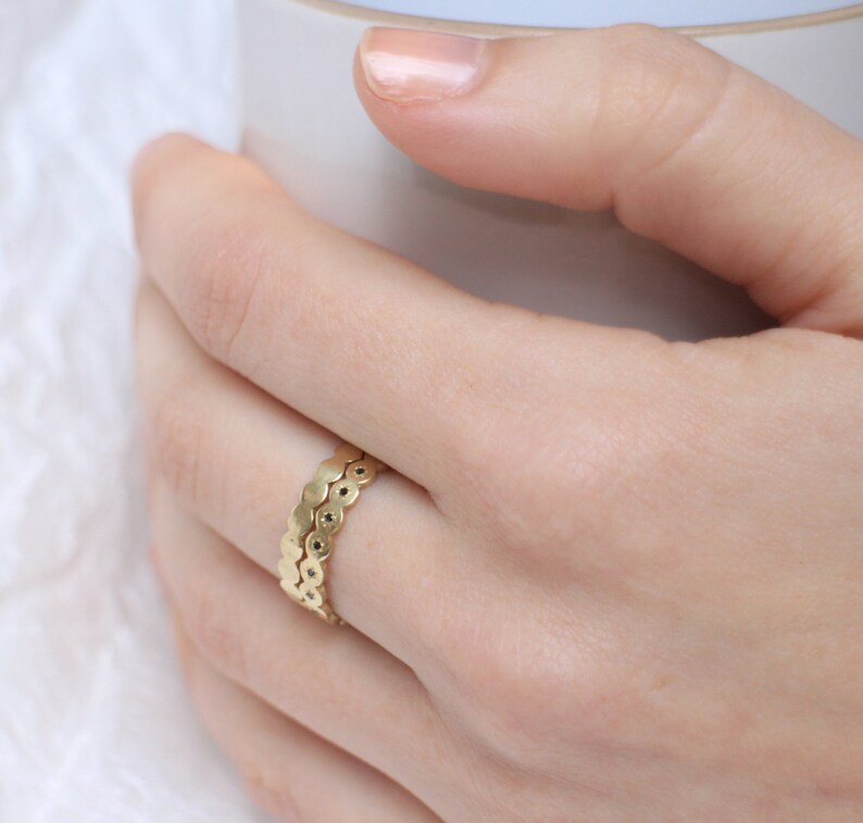 May include: A gold ring with a unique design featuring a double row of small, round, connected pieces.