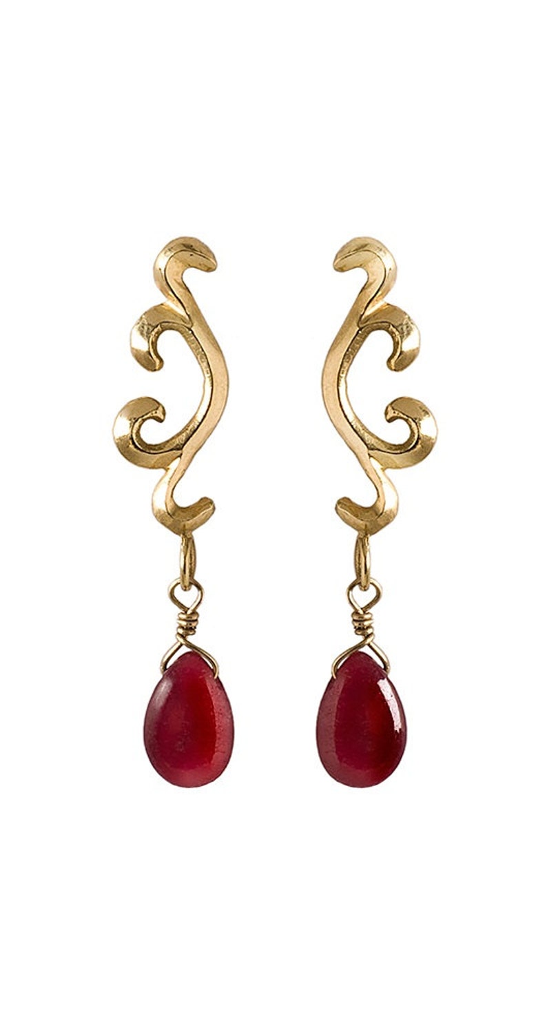 May include: Gold earrings with a delicate, swirling design and dangling red gemstone drops.
