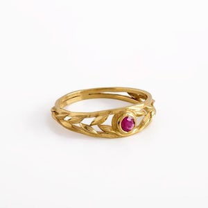 May include: A gold ring with a ruby gemstone set in a leaf design.
