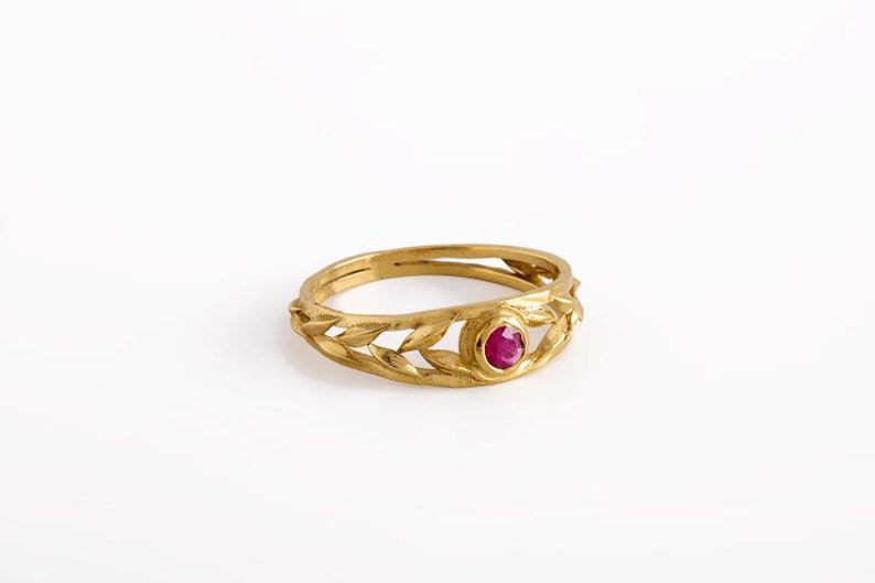 May include: A gold ring with a ruby gemstone set in a leaf design.
