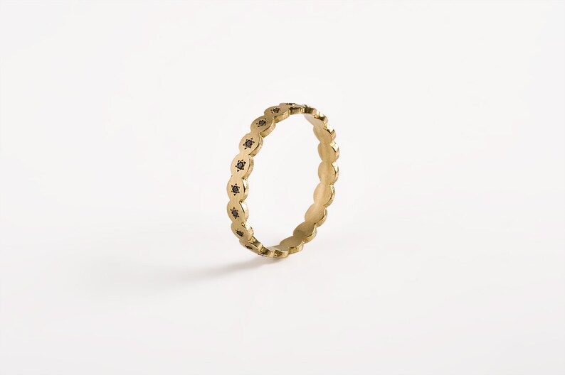 May include: A gold band ring with a scalloped edge and black diamonds set in each scallop.