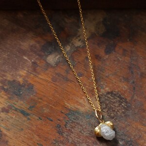 May include: A gold chain necklace with a rough, white diamond pendant.