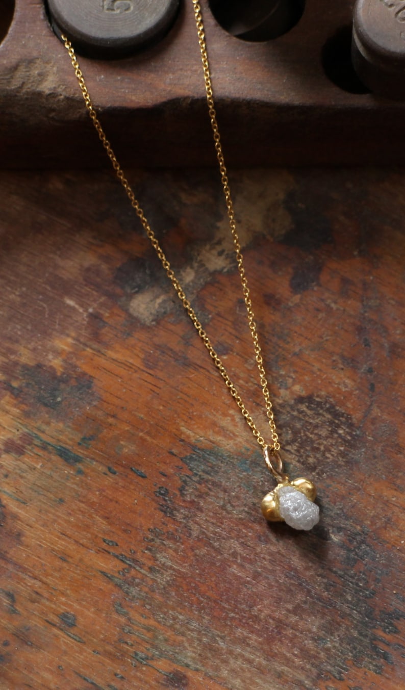 May include: A gold chain necklace with a rough, white diamond pendant.