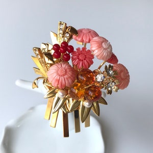 Puede incluir: Un peine de pelo dorado con flores rosas y rojas, cuentas de &aacute;mbar y pedrer&iacute;a transparente. El peine est&aacute; decorado con hojas doradas y tiene un dise&ntilde;o japon&eacute;s tradicional.