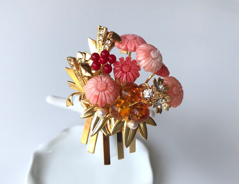 Puede incluir: Un peine de pelo dorado con flores rosas y rojas, cuentas de &aacute;mbar y pedrer&iacute;a transparente. El peine est&aacute; decorado con hojas doradas y tiene un dise&ntilde;o japon&eacute;s tradicional.