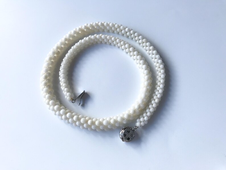 May include: A white pearl necklace with a silver clasp. The necklace is made of small, round pearls and is layered in a triple strand.