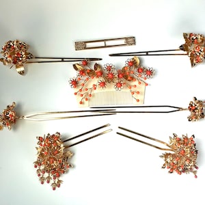 Op de afbeelding: Set van zeven gouden haar kammen met koraal gekleurde bloemen en kralen. De kammen zijn voor traditionele Japanse kapsels.