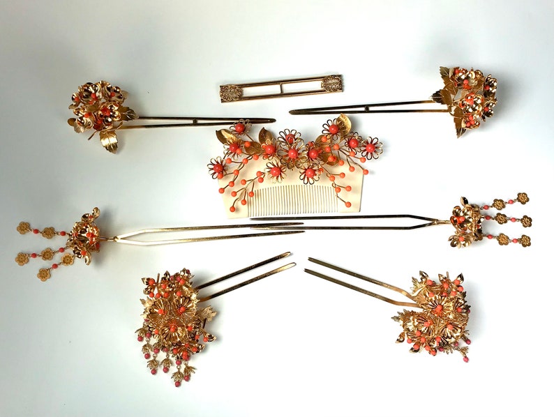 Op de afbeelding: Set van zeven gouden haar kammen met koraal gekleurde bloemen en kralen. De kammen zijn voor traditionele Japanse kapsels.